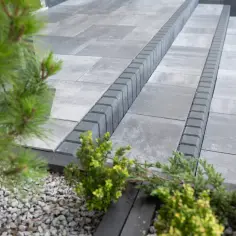 Nowoczesne aranżacje kostka brukowa wzory: szare płyty i obrzeża tworzą elegancką ścieżkę, otoczoną zielenią.