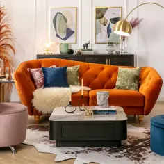 Salon w stylu francuskim: pomarańczowa kanapa, różowy fotel, złota lampa, dywan i dekoracje tworzą przytulną atmosferę.