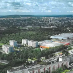 Widok z lotu ptaka na osiedle mieszkaniowe i centrum handlowe w otoczeniu zieleni.