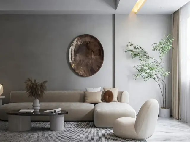 Nowoczesny salon w stylu minimalistycznym. Beżowa sofa, okrągły stolik kawowy, fotel i roślina w donicy tworzą przytulną przestrzeń.